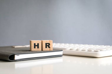 HR word on wood block cubes, on top of notepad and next to keyboard.