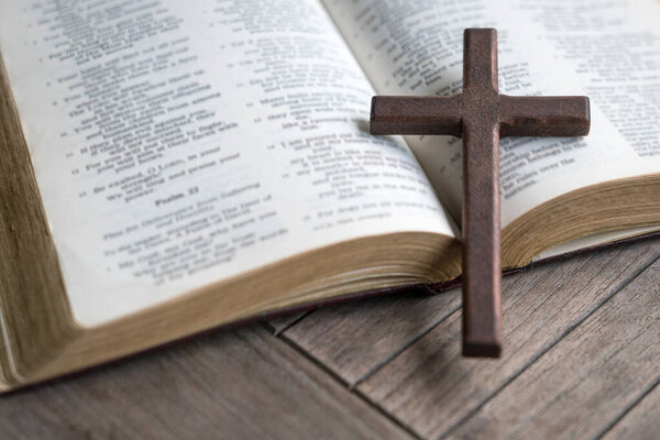 Wooden cross on top of an open bible. Copy space.