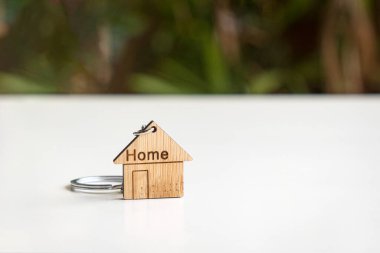 Ev şekilli anahtarlık beyaz masada, doğa kökenli. Boşluğu kopyala.