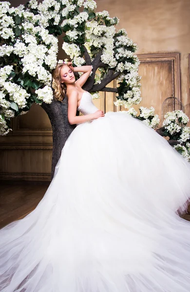 Schöne blonde Braut in einem luxuriösen Hochzeitskleid im Inneren — Stockfoto