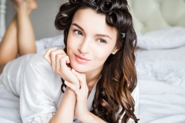 Beyaz ipek iç çamaşırlı güzel gelin bir sabah yatağında uzanıyor.