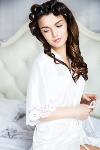 Hermosa novia en lencería de seda blanca en su dormitorio en una mañana — Foto de Stock