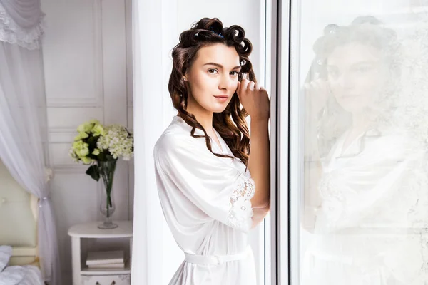 Beautiful bride in white silk lingerie in her bedroom near window in a morning — Stock Photo, Image