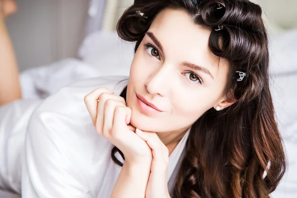 Beautiful bride in white silk lingerie lying on the bed in her bedroom in a morning — Stock Photo, Image