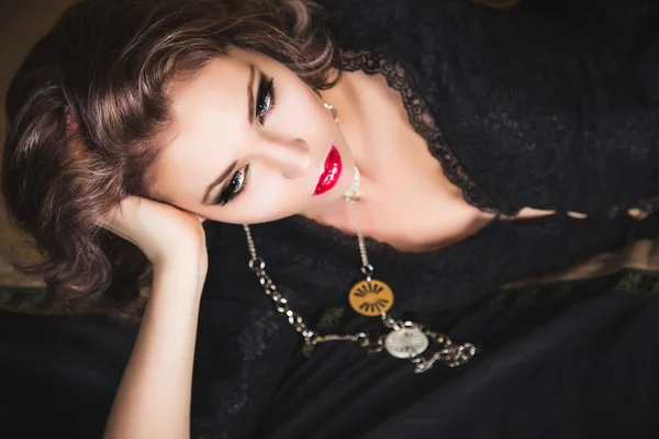 Close-up portrait of sexy dark haired girl in black dress posing on bed — Stock Photo, Image