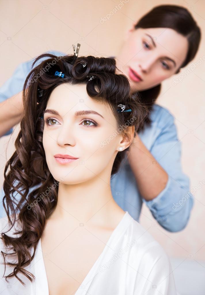 Hair Stylist preparing beautiful bride before the wedding in a morning