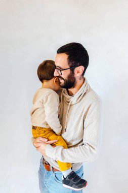 Beyaz arka planda oğlu kollarında genç bir baba. Baba ve bebek konsepti.