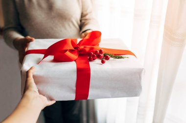 Bir kadın kırmızı kurdeleli Noel hediyesi kutusu veriyor. Xmas ve yeni yıl hediyesi, kış tatili.