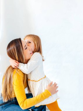 Genç iş kadını beyaz arka planda kızına sarılıyor. Genç İspanyol kadın. Anne-kız kavramı.