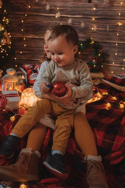 Αδελφή Κρατώντας Μικρό Αδελφό Της Στο Σαλόνι Διακοσμημένο Χριστουγεννιάτικο Δέντρο — Φωτογραφία Αρχείου