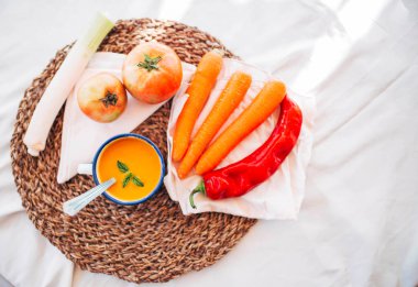 Vejetaryen balkabağı kreması ve sebzeli, biberli, pırasalı ve domatesli bir kupa.