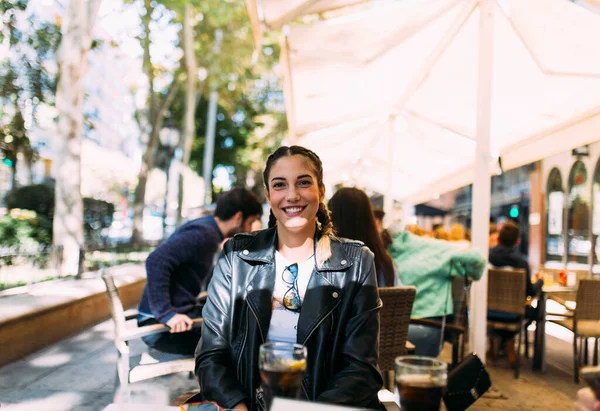 Açık hava barının terasında oturan mutlu genç bir bayan.