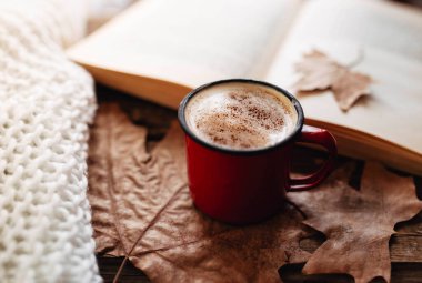 Sütlü kahve. Sonbaharda kitap okuyorum. Sonbahar yapraklı ahşap masa. Sabah rutini kakao ve tarçına odaklan..