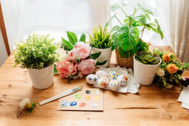 Modern paskalya yumurtaları boyalı. Çiçekler ve bitkilerle fırçalar ve boyalar. Ahşap arka planda mutlu paskalya konsepti.