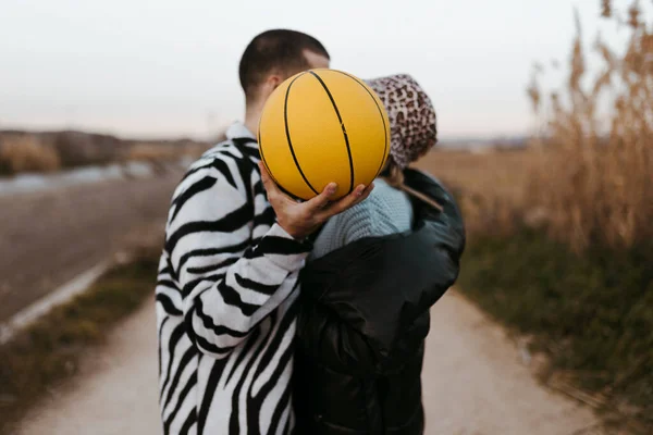 Jong Paar Stiekem Zoenen Achter Een Gele Basketbal — Stockfoto