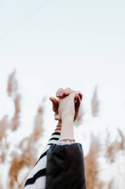 Bir çiftin birbirine bağlı ellerine yakın çekim. Kadın ve erkek birleşmiş