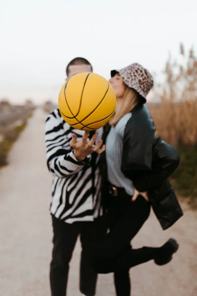 Paar Stiekem Zoenen Achter Een Gele Basketbal — Stockfoto