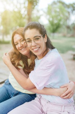 Kameraya bakıp gülümseyen iki mutlu kız arkadaş.