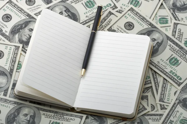 Notebook com caneta preta em notas de 100 dólares — Fotografia de Stock