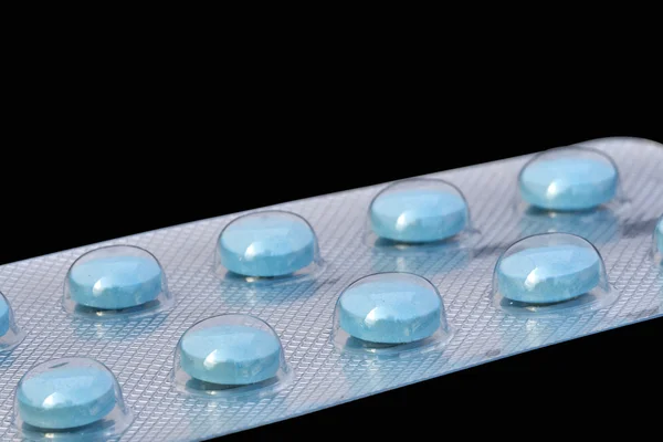 Puchýř modré tablety izolovaných na černém — Stock fotografie