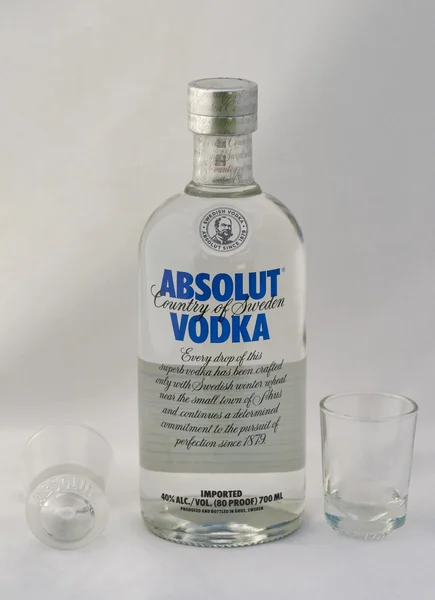Absolut vodka blue label and empty shot glasses — Stock Photo, Image