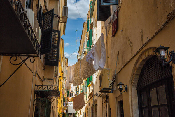The washed laundry is dried on the clothesline in narrow streets of Kerkyra, Island of Corfu, Greece.