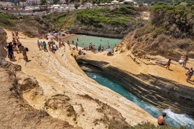Sidari, Korfu, Yunanistan - 01 Ağustos 2021: İnsanlar ünlü Kanal D 'amour' da yüzüyor ve güneşleniyor. Sidari, Korfu adasının kuzey kesiminde bir yerleşim yeridir..