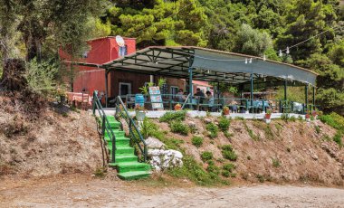 Glyfada, Corfu, Yunanistan - 06 Ağustos 2021: İnsanlar Mirtiotissa plajı yakınlarındaki küçük kırsal Yunan tavernasını ziyaret ediyorlar. Korfu, İyon Denizi 'nde bir Yunan adasıdır..