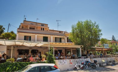 Kassiopi, Korfu, Yunanistan - 07 Ağustos 2021: Korfu adasının kuzeydoğu kıyısındaki Kassiopi limanındaki kafe ve restoranları ziyaret edenler.