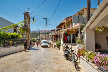 Kassiopi, Korfu, Yunanistan - 07 Ağustos 2021: Korfu adasının kuzeydoğu kıyısındaki Kassiopi caddesi boyunca insanlar yürüyor.