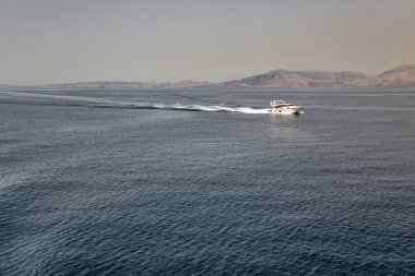 Seascape with speed motor boat sails in the distance off the coast of Greece