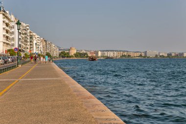 Thessaloniki, Greece - July 27, 2021: Cityscape with people walking along waterfront. It is the second largest city in Greece and the capital of geographic region of Macedonia.