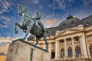 Dramatic sunset sky and equestrian statue of Carol I in front of University Library in Bucharest, Romania