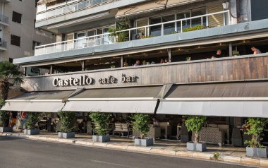 Thessaloniki, Greece - July 27, 2021: People visit cafe bar Castello on waterfront. Thessaloniki is the second largest city in Greece and the capital of geographic region of Macedonia.