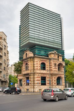 Bükreş, Romanya - 12 Ağustos 2021: McKinsey and Company ve Ulusal Mimarlar Sendikası Genel Merkezi (UAR) şehir merkezindeki ofis binası. Eski tarihi bir binanın tepesindeki modern cam bina..