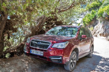Glyfada, Corfu, Yunanistan - 06 Ağustos 2021: Deniz kıyısına park etmiş Cherry Subaru Forester. 1997 yılından beri üretilen kompakt bir SUV (spor amaçlı araç)..