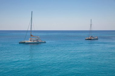 Ayia Napa, Kıbrıs - 24 Mayıs 2021: Cennet turkuaz gölünde güzel katamaranlar II. Ayia Napa, Kıbrıs 'ın güney kıyılarının uzak doğu ucunda bir turizm beldesi..