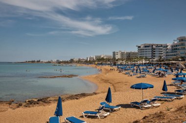 Protaras, Kıbrıs - 25 Mayıs 2021: İnsanlar lüks otellerle tatil beldelerinde güneşlenip dinleniyorlar. Protaras açık gökyüzü mavi sulara ve kumlu plajlara sahiptir. Bunların en ünlüsü İncir Ağacı Koyu 'dur..