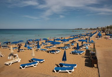 Protaras, Kıbrıs - 25 Mayıs 2021: İnsanlar lüks otellerin plajlarında güneşlenip dinleniyorlar. Protaras açık gökyüzü mavi sulara ve kumlu plajlara sahiptir. Bunların en ünlüsü İncir Ağacı Koyu 'dur..