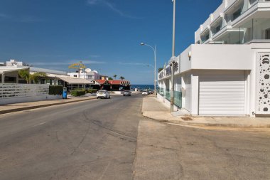 Protaras, Kıbrıs - 25 Mayıs 2021: Rising Sun pub ile denize açılan sokak. Protaras açık gökyüzü mavi sulara ve kumlu plajlara sahiptir. Bunların en ünlüsü İncir Ağacı Koyu 'dur..