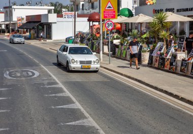 Ayia Napa, Kıbrıs - 31 Mayıs 2021: Nissi Bulvarı 'ndaki beyaz Mercedes 6 kapılı taksi. Ayia Napa, Kıbrıs 'ın güney kıyılarının uzak doğu ucunda bir turizm beldesi..