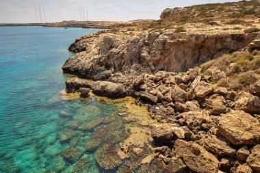 Seascape Cape Greco yarımadası parkı, Kıbrıs. Ulusal parkı, kaya yolları, turkuaz bir gölü ve doğal bir taş köprüsü olan dağlık bir yarımadadır..