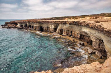 Seascape Cape Greco yarımadası parkı, Kıbrıs. Ulusal parkı, kaya yolları, turkuaz bir gölü ve doğal bir taş köprüsü olan dağlık bir yarımadadır..