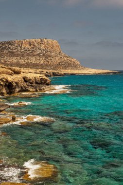 Seascape Cape Greco yarımadası parkı, Kıbrıs. Ulusal parkı, kaya yolları, turkuaz bir gölü ve doğal bir taş köprüsü olan dağlık bir yarımadadır..