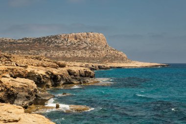 Seascape Cape Greco yarımadası parkı, Kıbrıs. Ulusal parkı, kaya yolları, turkuaz bir gölü ve doğal bir taş köprüsü olan dağlık bir yarımadadır..