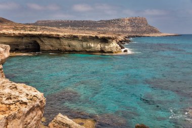 Seascape Cape Greco yarımadası parkı, Kıbrıs. Ulusal parkı, kaya yolları, turkuaz bir gölü ve doğal bir taş köprüsü olan dağlık bir yarımadadır..