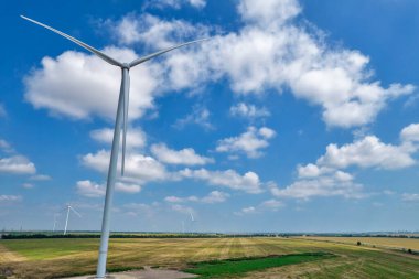 Drone view over wind farm turbine closeup against blue sky with clouds.