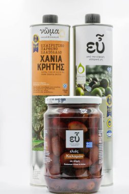 Corfu, Greece - August 15, 2021: Studio shoot of Xania Crete olive oil extra virgin tins and EU olives jar closeup on white.