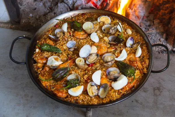 Paella apetitosa cocinada sobre un fuego de leña —  Fotos de Stock