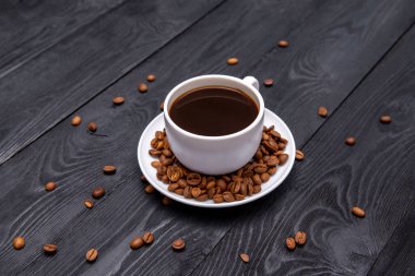 Kahve fincanı siyah ahşap masada kahve çekirdeklerini sarmıştı.